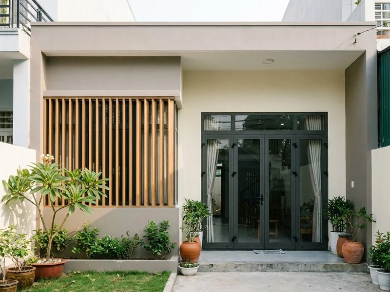 Mặt tiền nhà cấp 4 sau cải tạo với cửa kính lớn và lam gỗ chắn nắng