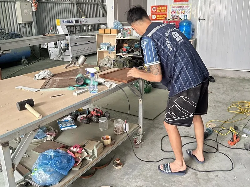 Thợ Nhà Mộc hoàn thiện cánh tủ trên bàn máy tại xưởng