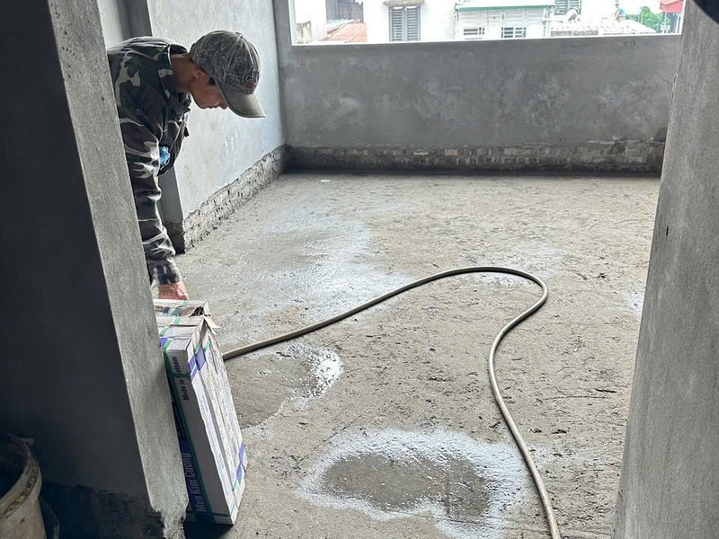 Thợ làm ẩm, vệ sinh mặt sàn trước khi lát gạch tại công trình nhà phố Sơn Đồng, Hoài Đức — Nhà Mộc thi công