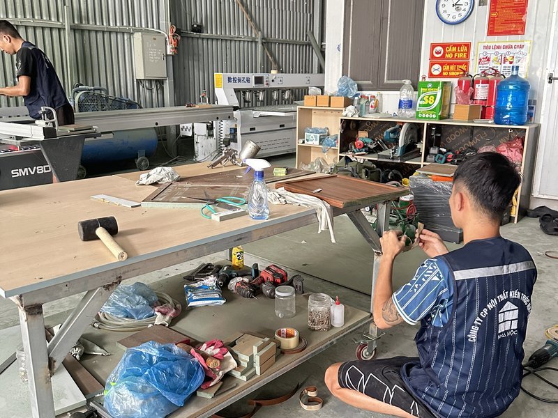 Thợ Nhà Mộc lắp ráp, hoàn thiện cánh tủ tại bàn thao tác trong xưởng Cát Quế